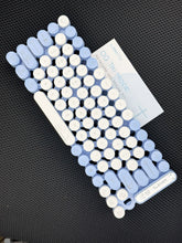 Blue and white穴位贴片 on a black textured surface with a leaflet.